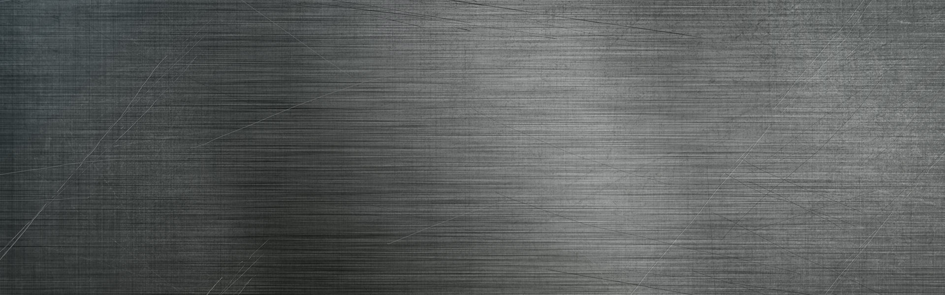 This image shows a wide, textured metallic surface with scratches and a brushed appearance in a monochromatic, dark grey color scheme, conveying an industrial feel.