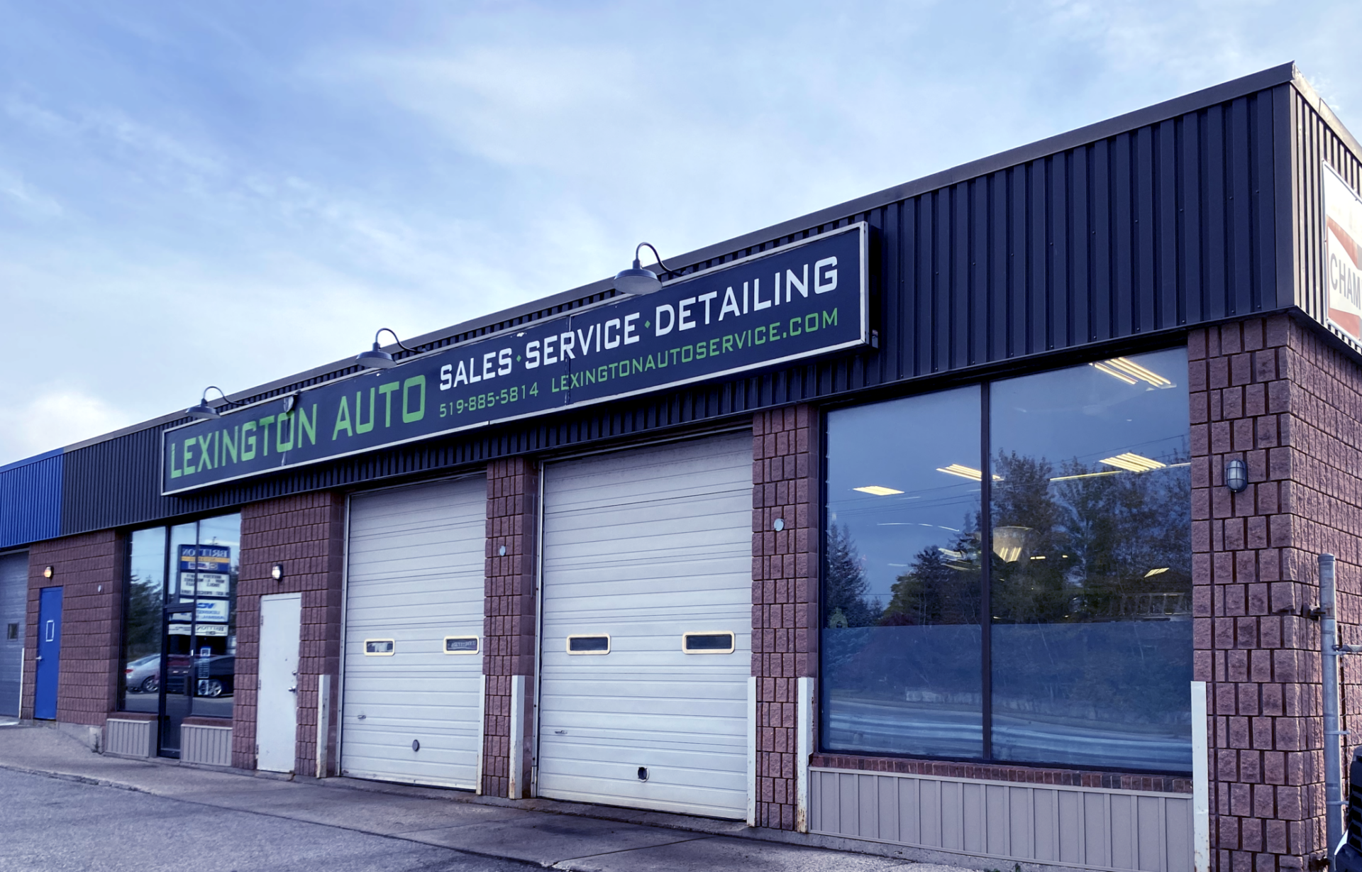This image shows the exterior of Lexington Auto, an automotive business offering sales, service, and detailing, with a blue and brick facade and garage doors.